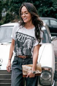 Beautiful young woman standing in car