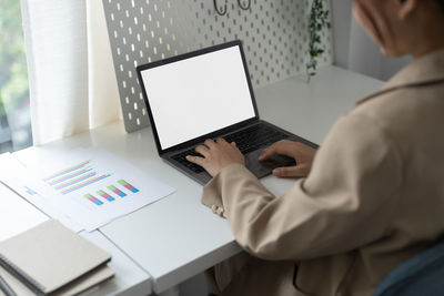 Midsection of businessman using laptop at office