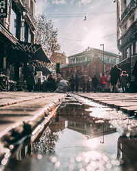 People walking on street by buildings in city