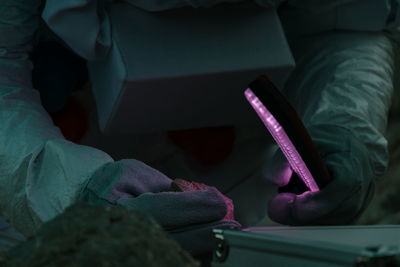 Midsection of person examining rock on table