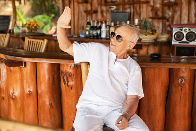 Portrait of young man wearing sunglasses while sitting on table