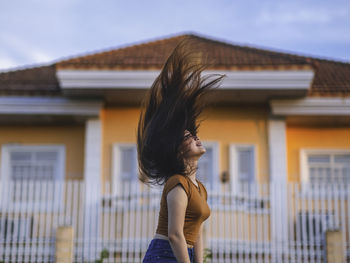 Side view of woman standing against building