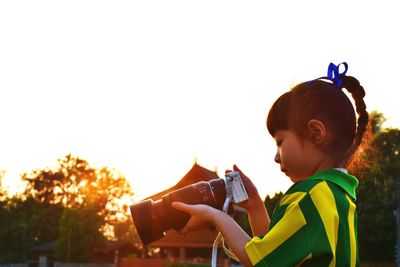 Side view of boy holding umbrella against clear sky