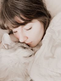 Close-up of woman cuddling cat on bed at home