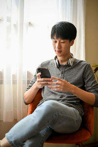 Young woman using laptop while sitting on sofa at home