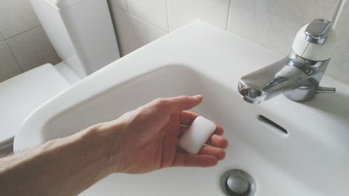 Close-up of hand on faucet at home