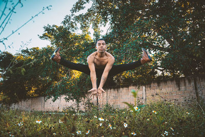 Full length of shirtless young man against trees