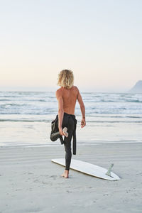 Rear view of woman standing at beach