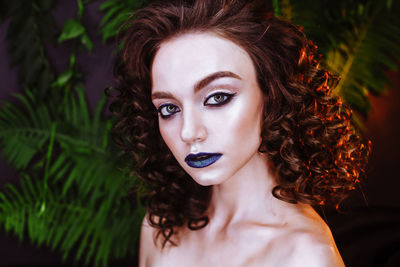 Portrait of beautiful redhead woman wearing make-up by plants