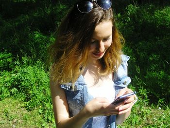 Young woman using smart phone in grass