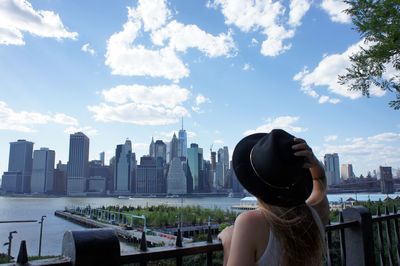 Rear view of woman looking at modern buildings against sky