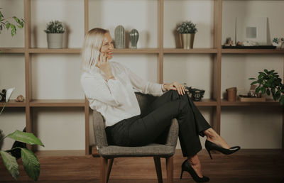 A confident businesswoman sitting on the chair working over the project and talking on the phone