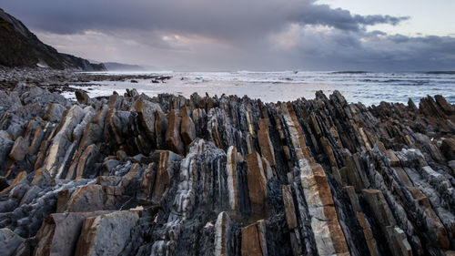 Panoramic view of flysch cliff rock structures at basque sea against sky