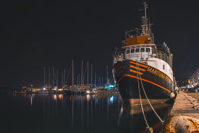 Sailboats moored at harbor against sky at night