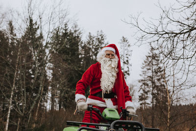 Man wearing santa costume riding lawn mower