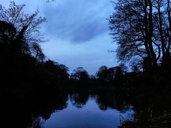 Silhouette trees by lake against sky during sunset