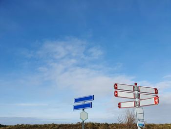 Low angle view of road sign against blue sky