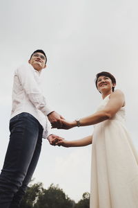 Low angle view of friends standing against sky