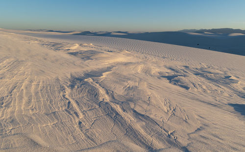 Hard sand formations poking through the white sands dunes at sunset in white sands national park