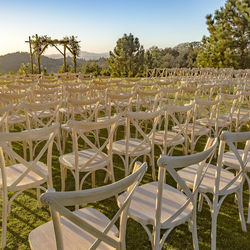 Empty chairs on field against sky