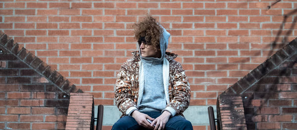 Woman sitting against brick wall