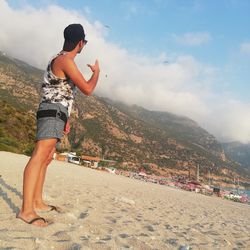 Midsection of woman standing on mountain against sky