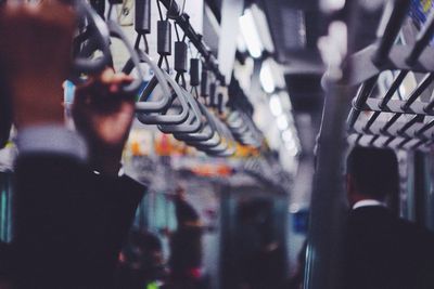 Cropped image of people holding handles in subway train 