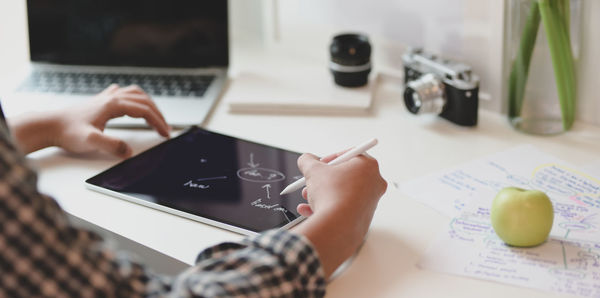 Midsection of woman using technology on table