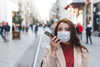 Portrait of young woman standing on street in city