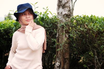 Portrait of young woman standing against plants