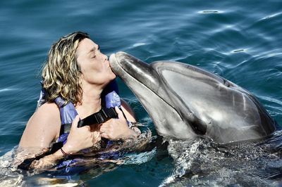 Photo of female  kissing a dolphin close up 