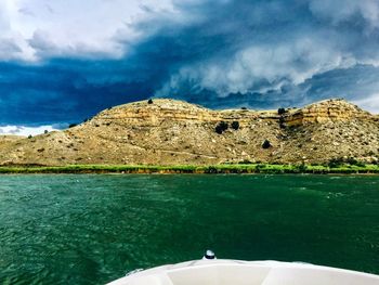 Scenic view of sea by mountain against sky