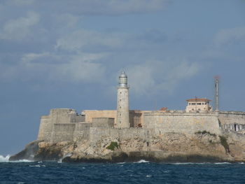 Lighthouse by sea against sky