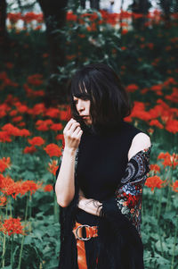 Young woman standing on red flowering plants