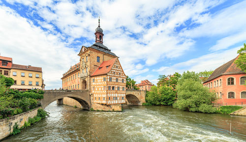 Arch bridge over river amidst buildings against sky