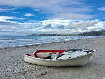 Boat moored on beach against sky