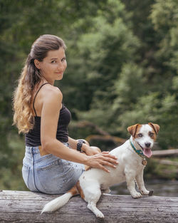 Portrait of young woman with dog sitting outdoors