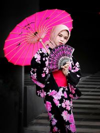 Woman with pink umbrella standing in rain