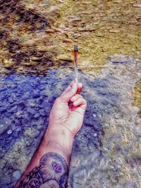 High angle view of woman hand with tattoo on water