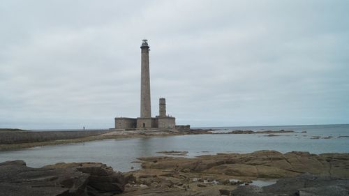 Lighthouse by sea against sky