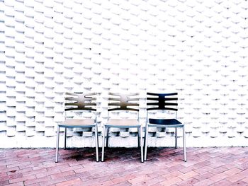 Empty chairs against white wall