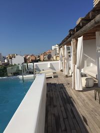 View of swimming pool by building against clear blue sky