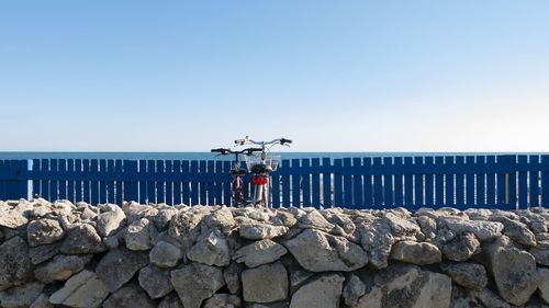 Deck chairs on rocks against clear blue sky