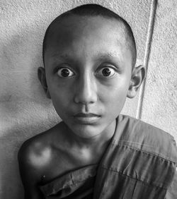 Close-up portrait of shirtless boy against wall