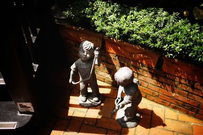 Statue of boy walking against plants