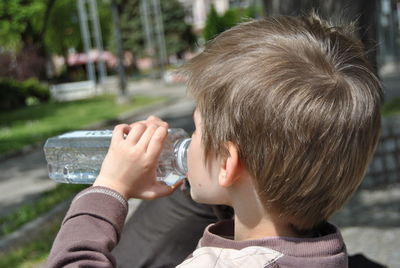 Boy drinking water from bottle in city