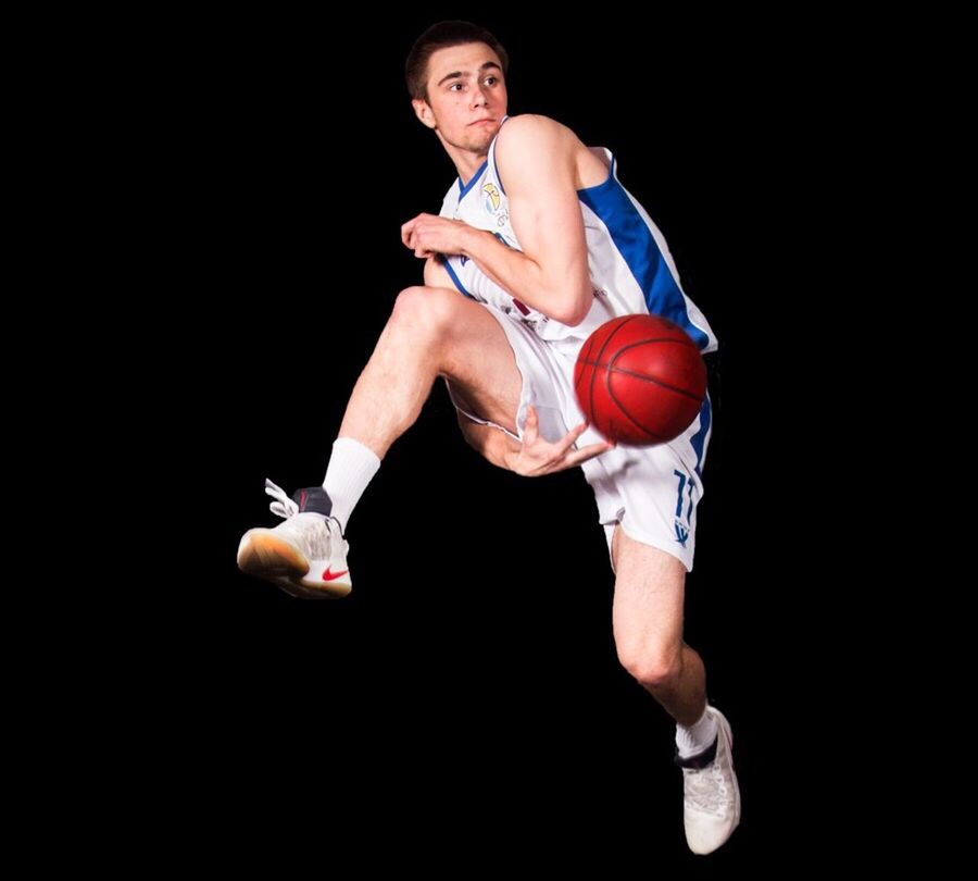 YOUNG MAN PLAYING WITH BALL AGAINST GRAY BACKGROUND