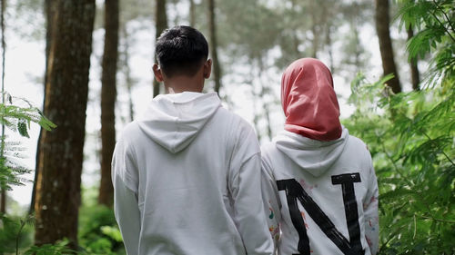 Rear view of couple walking in forest