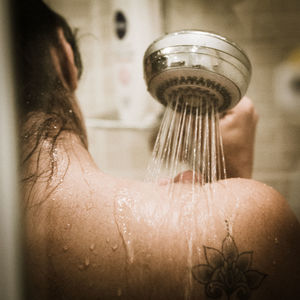 Cropped image of woman taking shower in bathroom