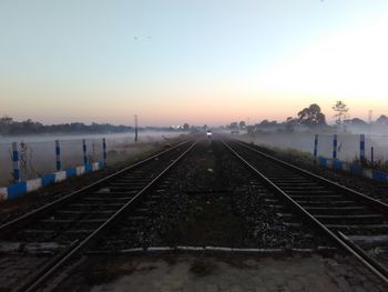 Railroad tracks against sky during sunset